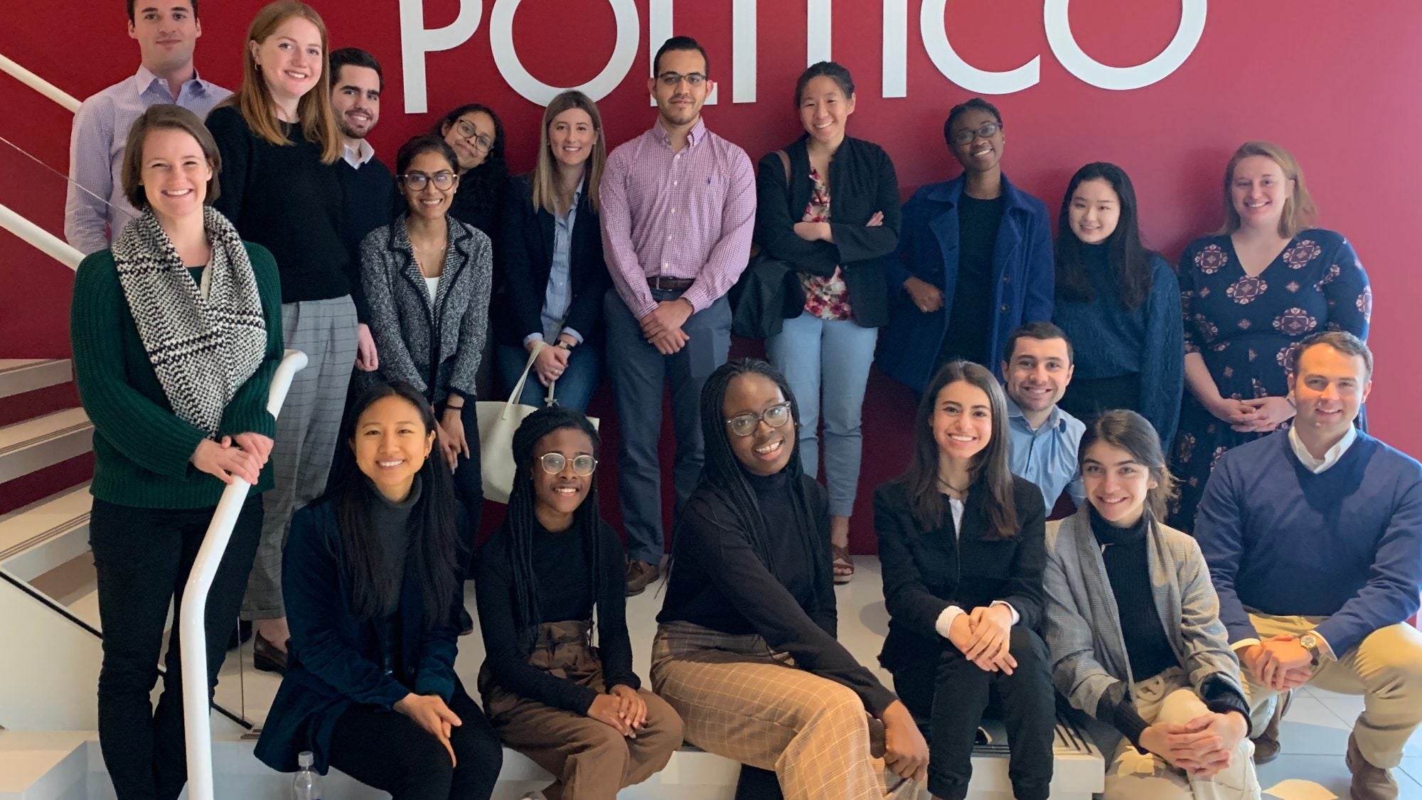 Students smile for photo in front of &quot;Politico&quot; sign.