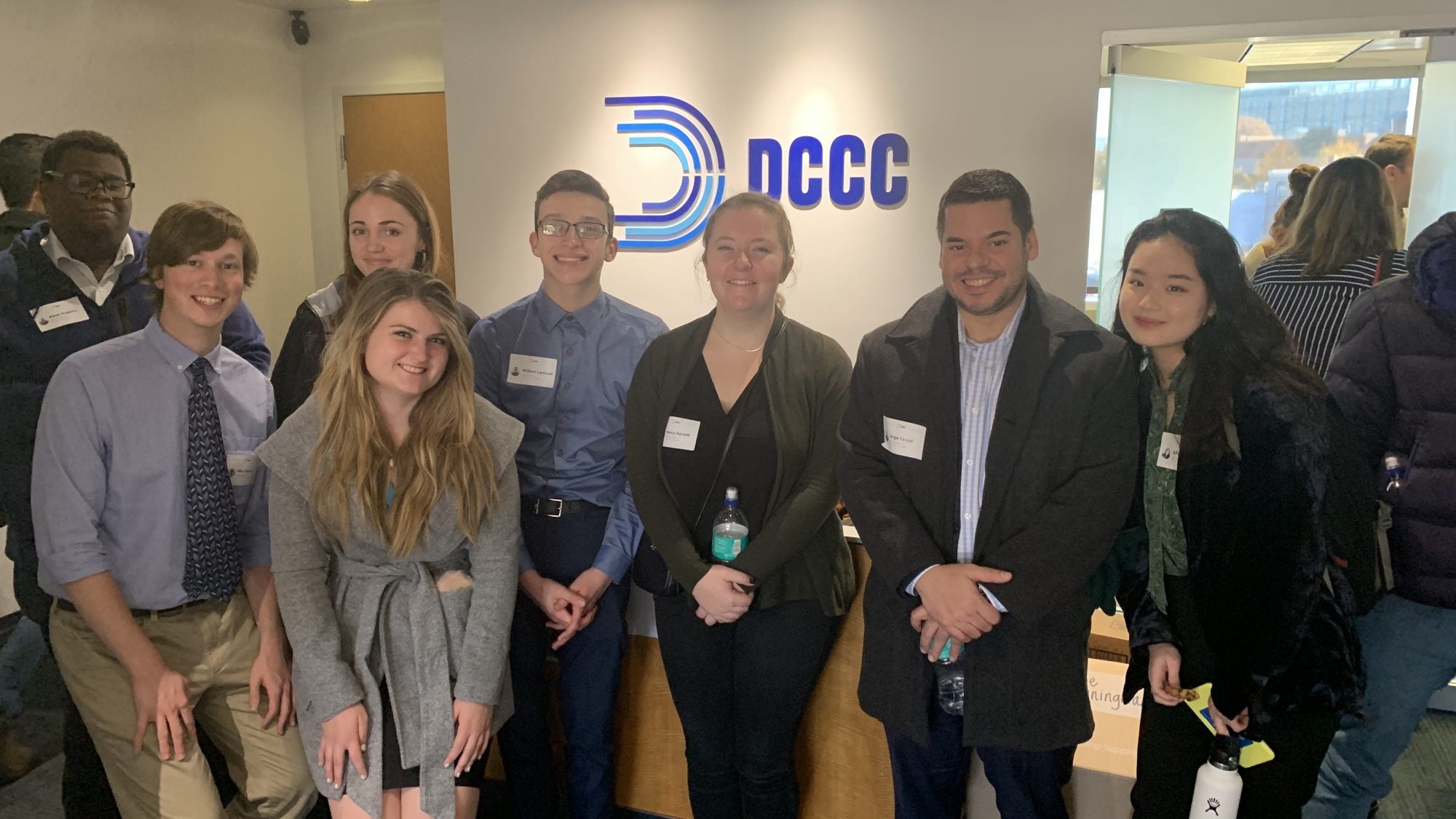 Students stand in NCCC office in front of NCCC logo.