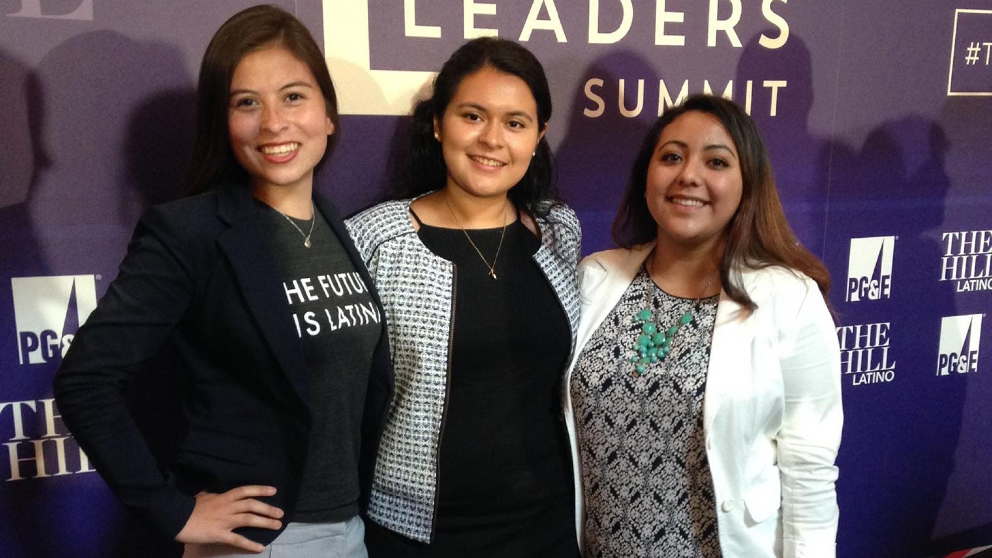 Students stand in front of sign that reads &quot;Latina Leaders Summit&quot;