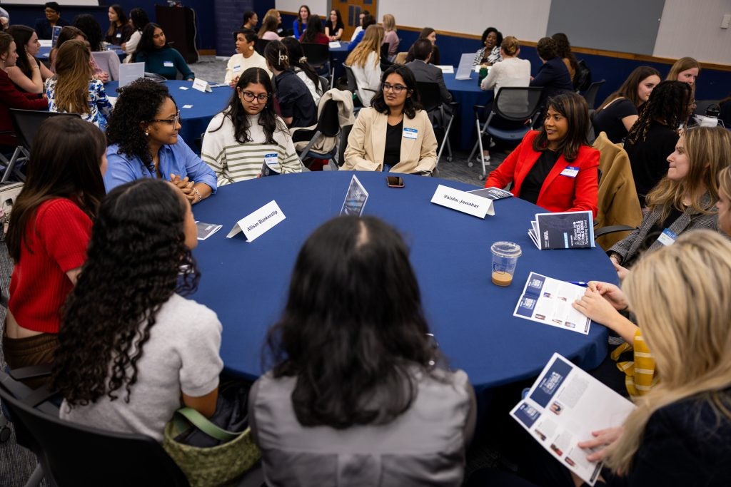 Students and participants chat at a round table.
