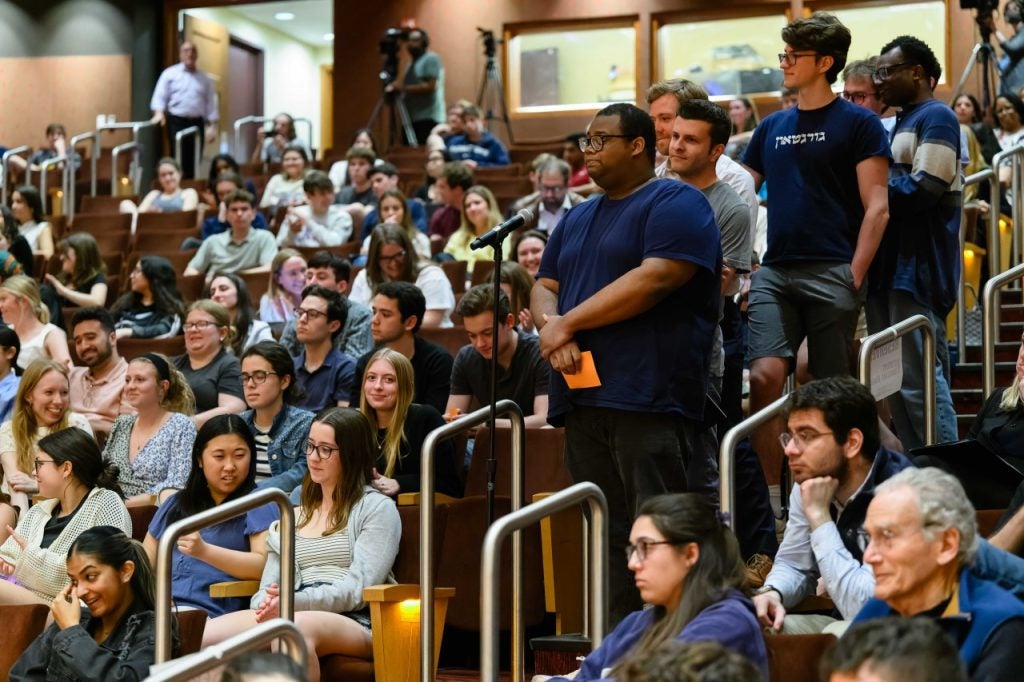 A student asks a question from a microphone in the aisle.