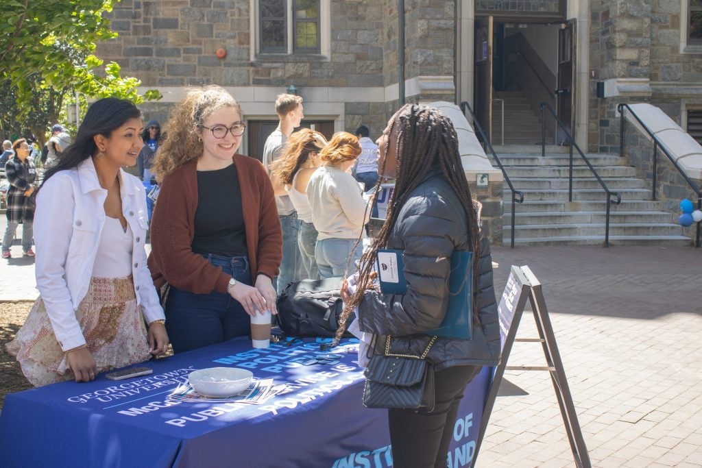 Students tabling outside talking to another student.