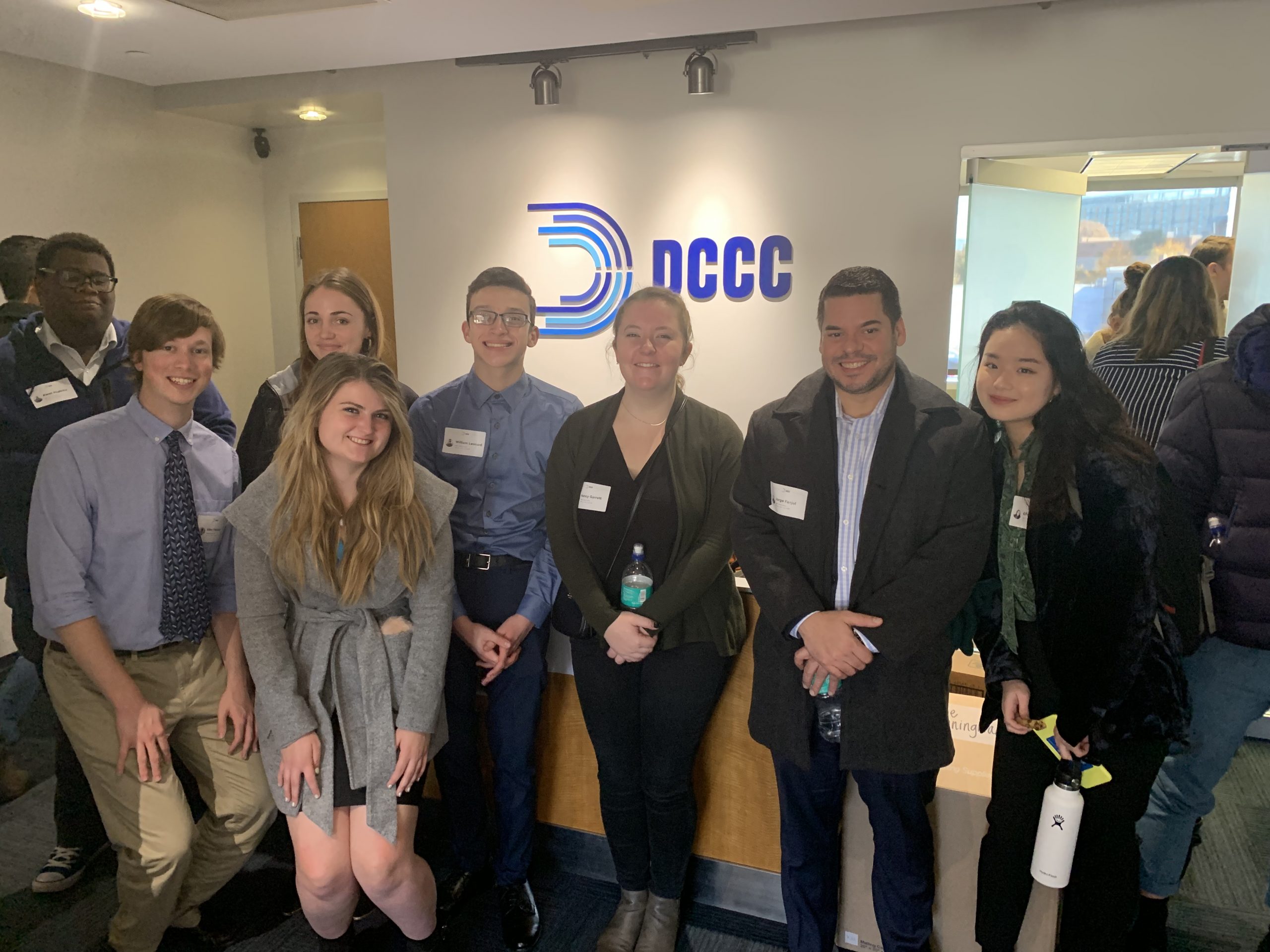 Students stand in NCCC office in front of NCCC logo.