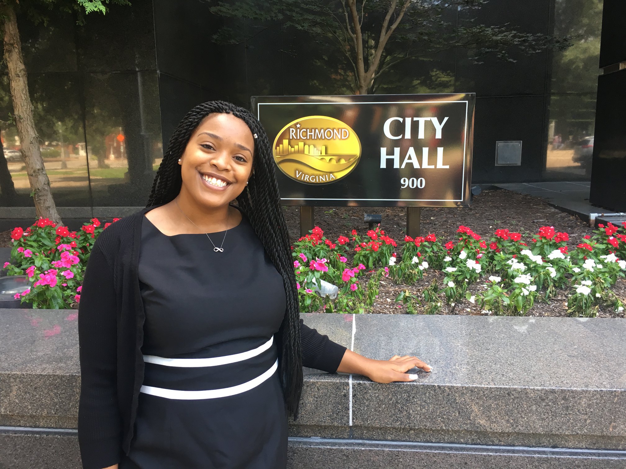 Student stands in front of Richmond City Hall sign.
