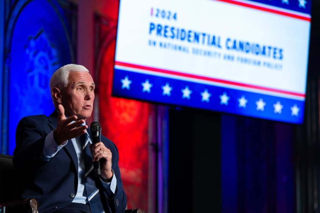 Mike Pence speaks with TV screen background reading 2024 Presidential Candidates.