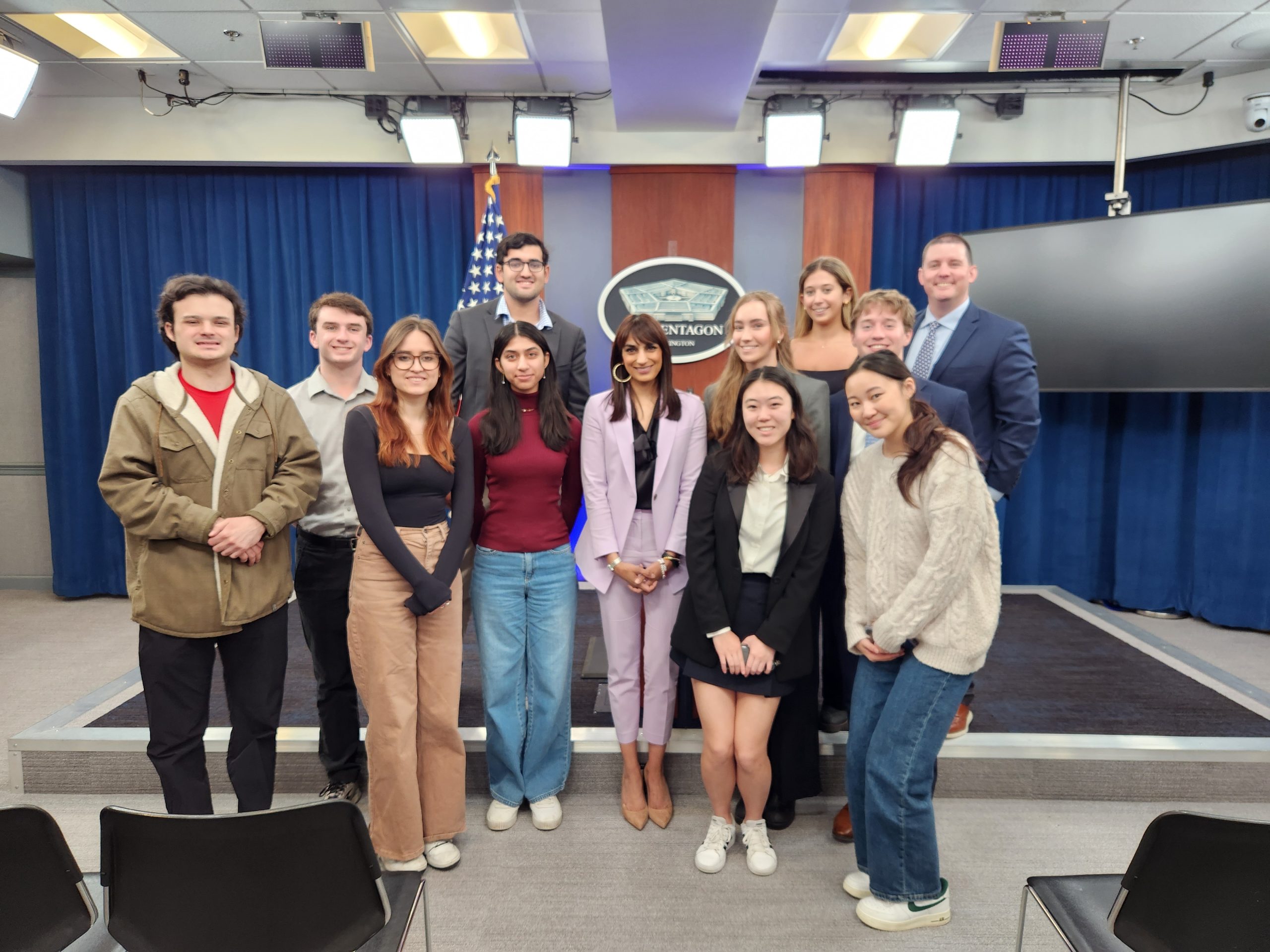 Students stand in front of podium at Pentagon press briefing room.