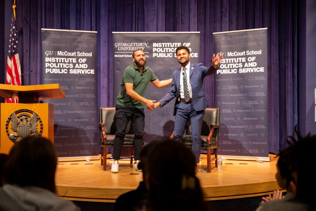 Frost smiles and waves as he shakes Lowery's hand on stage.