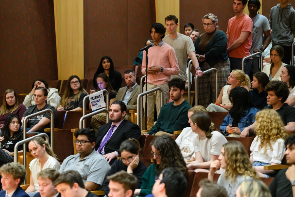 A student asks a question from a microphone in the aisle.
