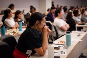 A student rests her hands on her mouth tensely watching.
